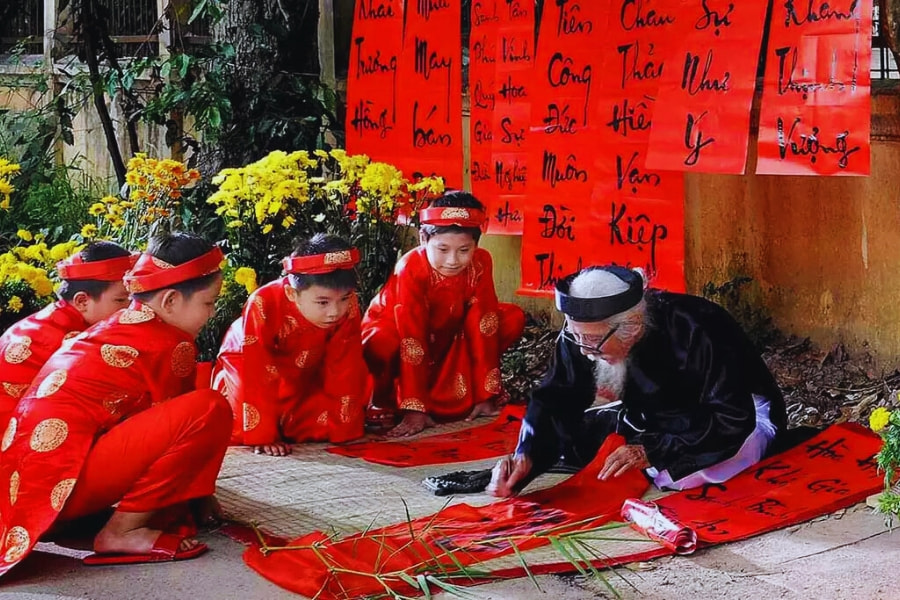 Vietnam Tet calligraphy master writing lucky words for children in traditional ao dai